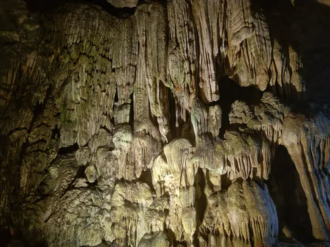 Illuminated stalactites and stalagmites inside a limestone cave.