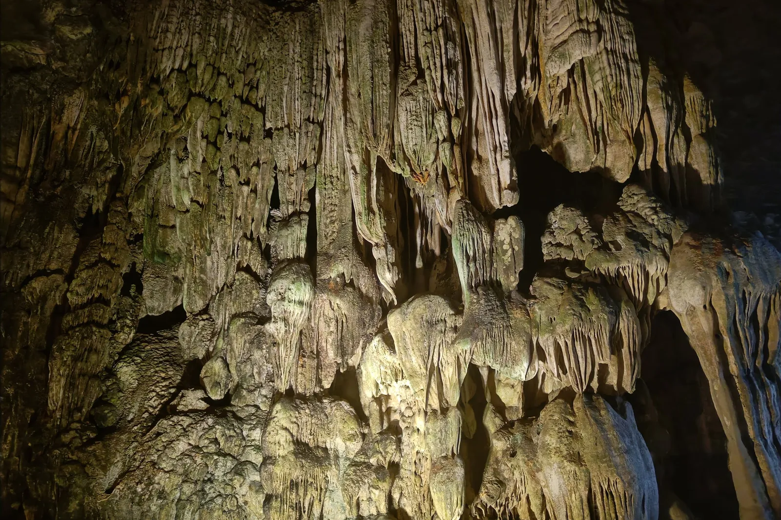 Illuminated stalactites and stalagmites inside a limestone cave.