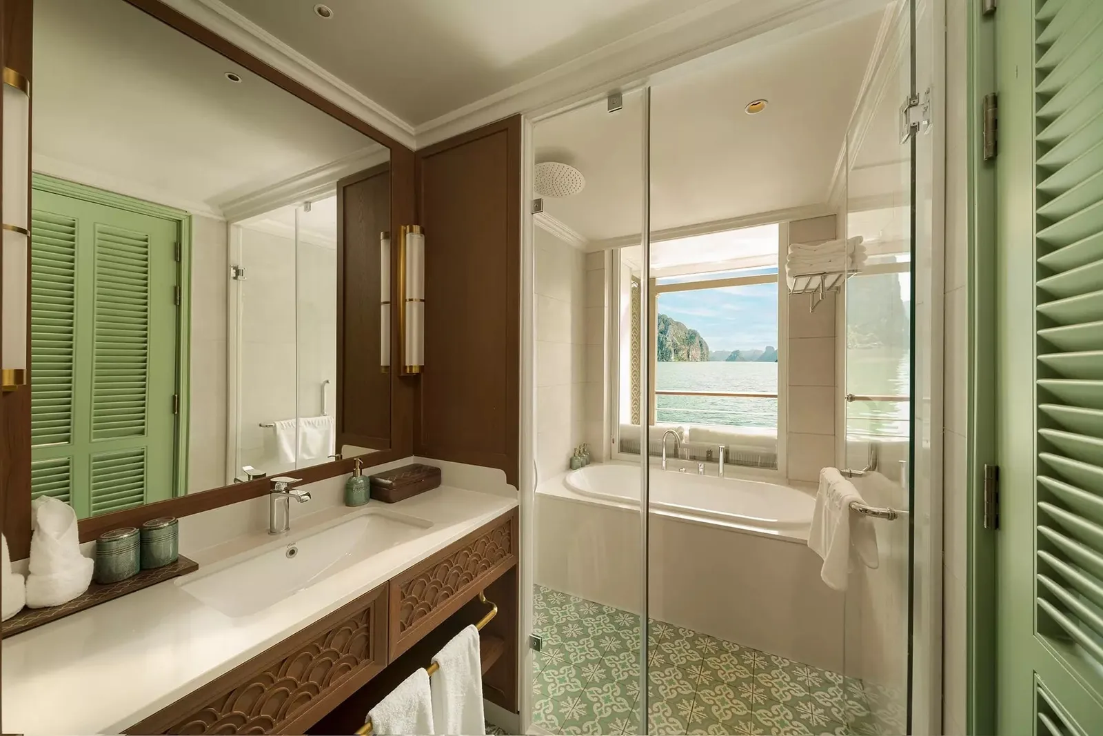 A luxury boat cabin bathroom with a bathtub, shower, vanity, and a window showing karst limestone islands and water characteristic of Ha Long Bay.