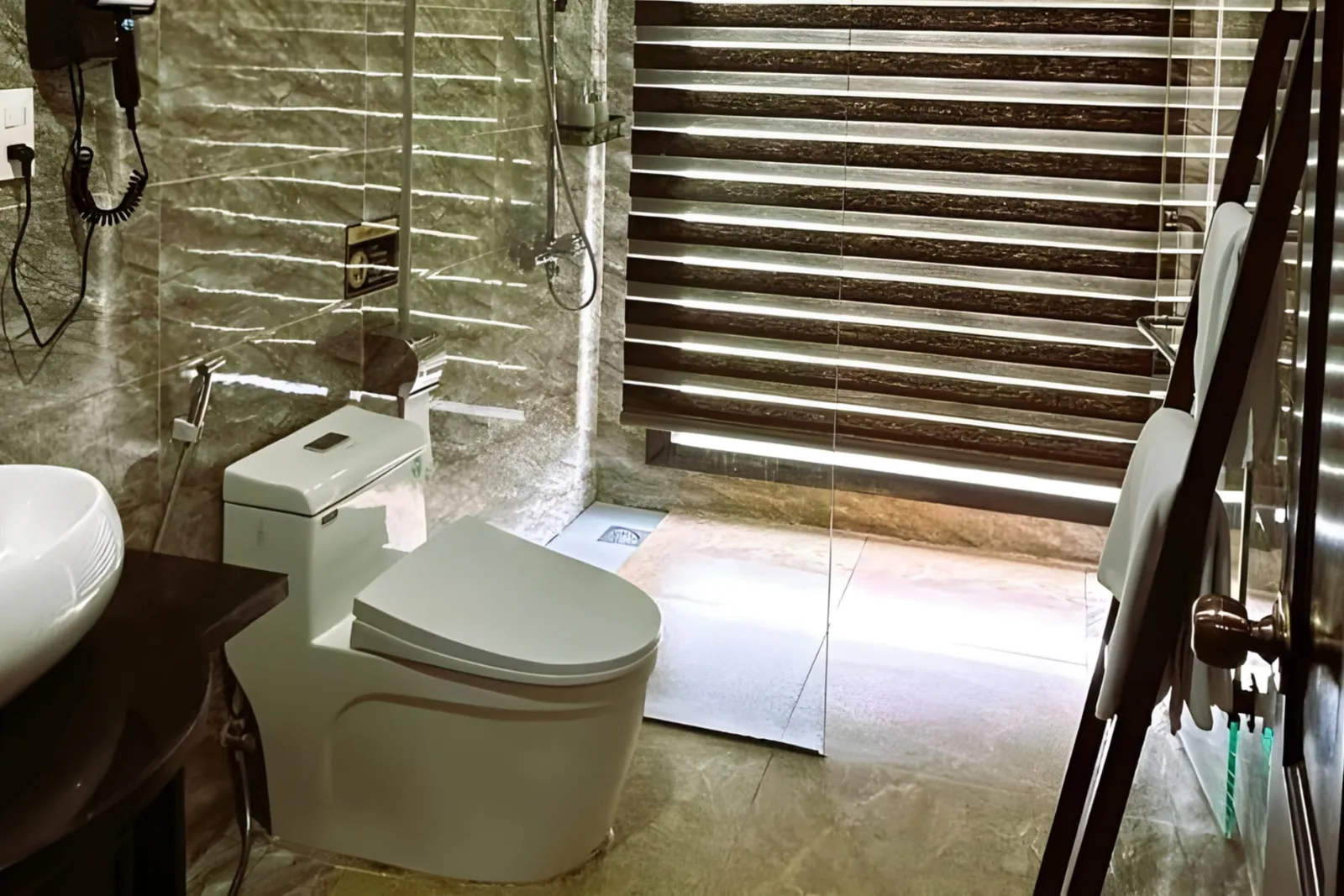 A bathroom with a vessel basin, a toilet and a glass shower with a roller blind.
