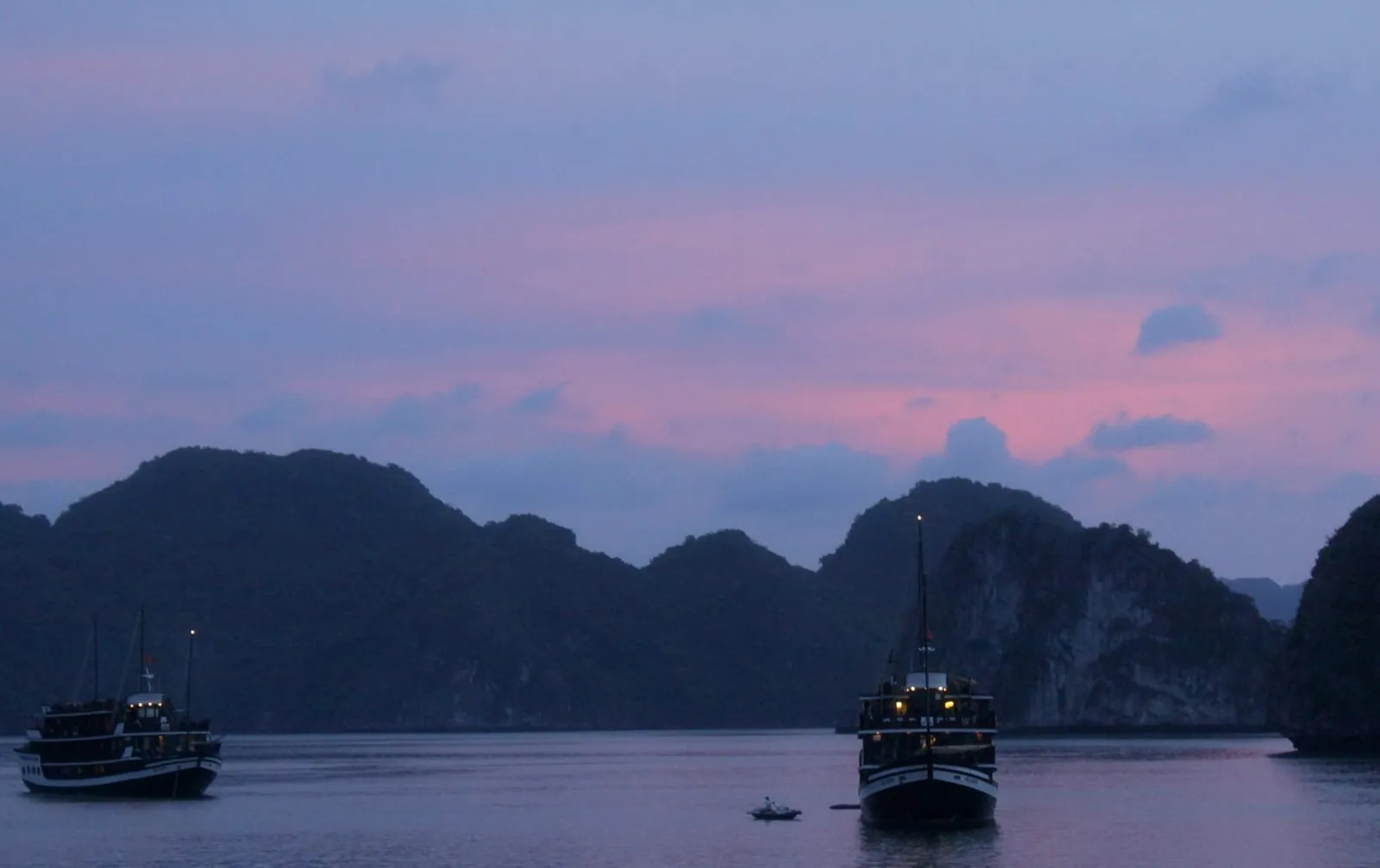 Two cruise boats at anchor among limestone islands at dusk