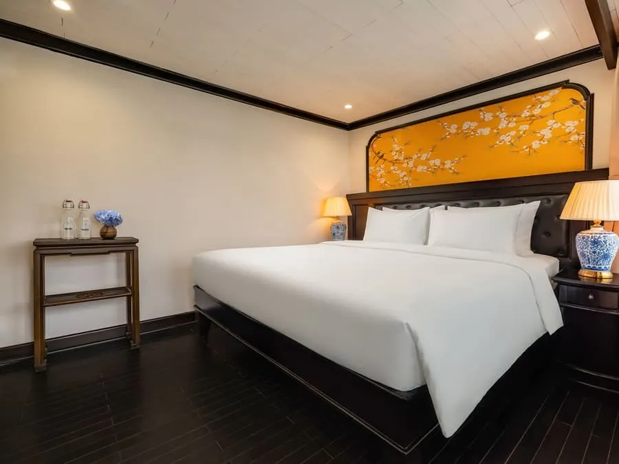 A double cabin with a white bed under a yellow blossom-painted headboard and dark timber floor.