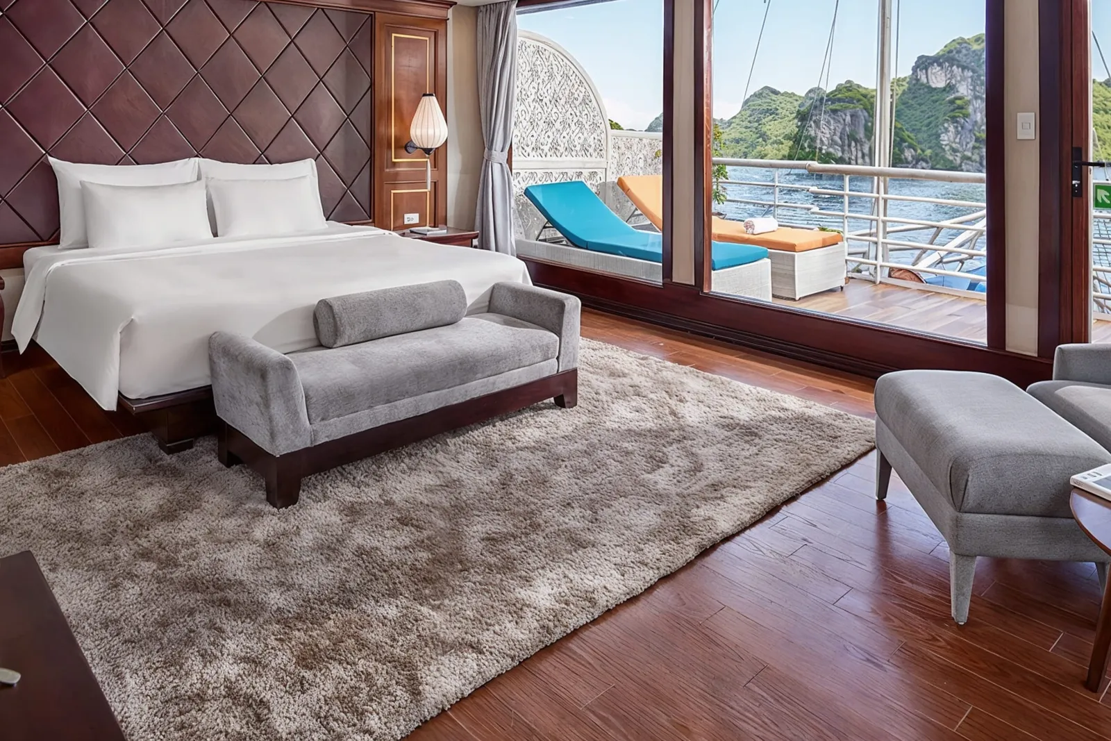 A cabin with a dark leather diamond-pattern headboard, a white bed and a grey bench by the windows.