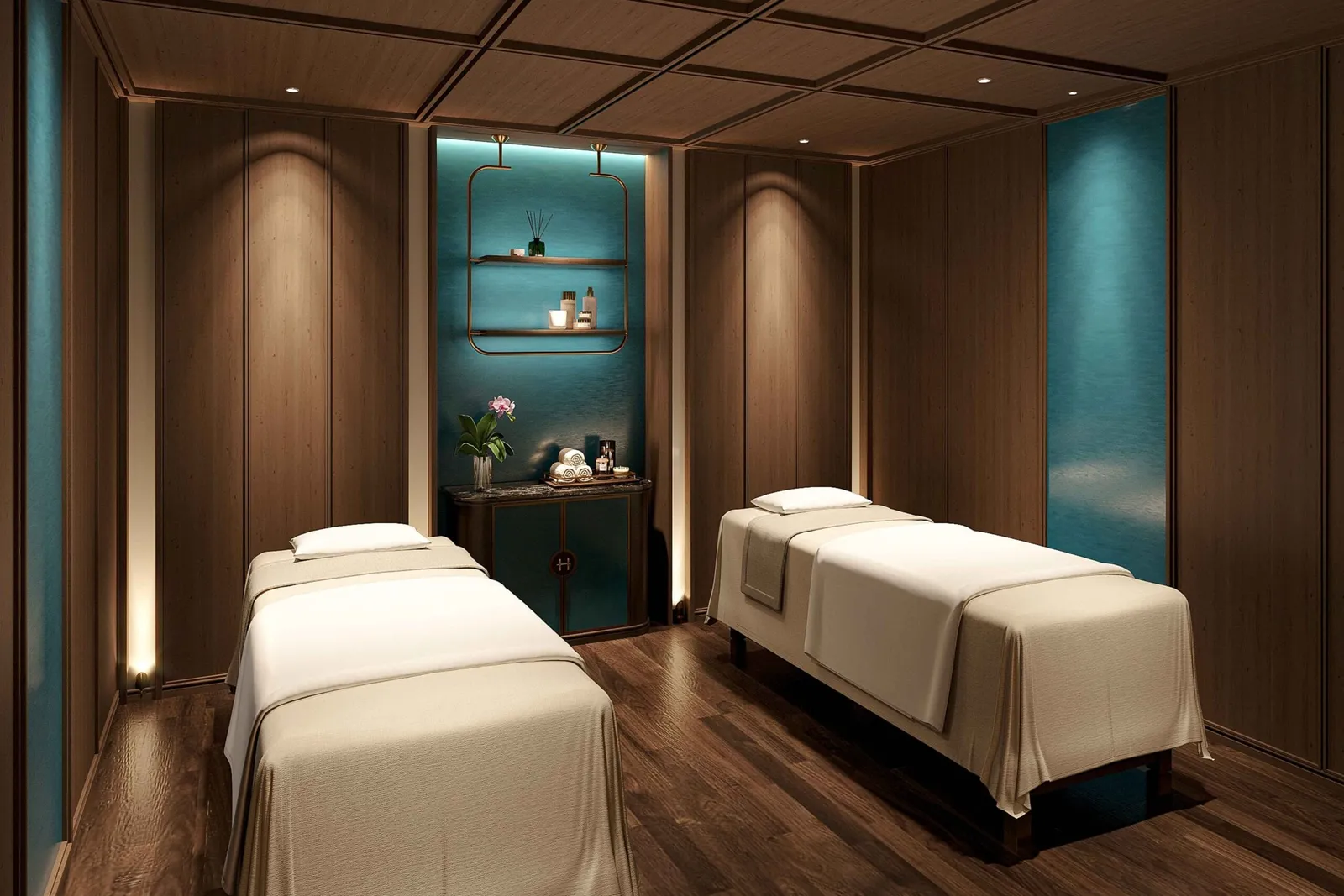 A spa or massage room with two treatment beds, wood paneling, teal accent walls, and shelving with amenities between the beds.