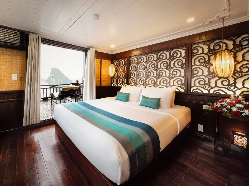 A double cabin with a balcony door, a carved headboard and a flower arrangement.