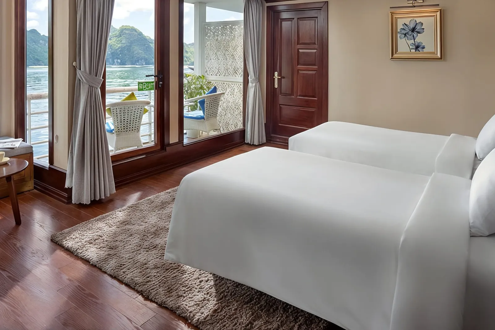 A white bed, a rug and a round table in front of glass balcony doors with a view of karst.