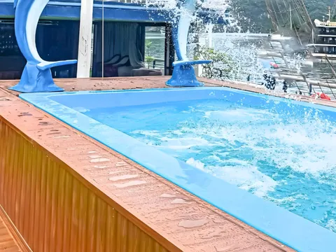 A plunge pool with two blue dolphin statues spouting water on the upper deck, with sail rigging behind.