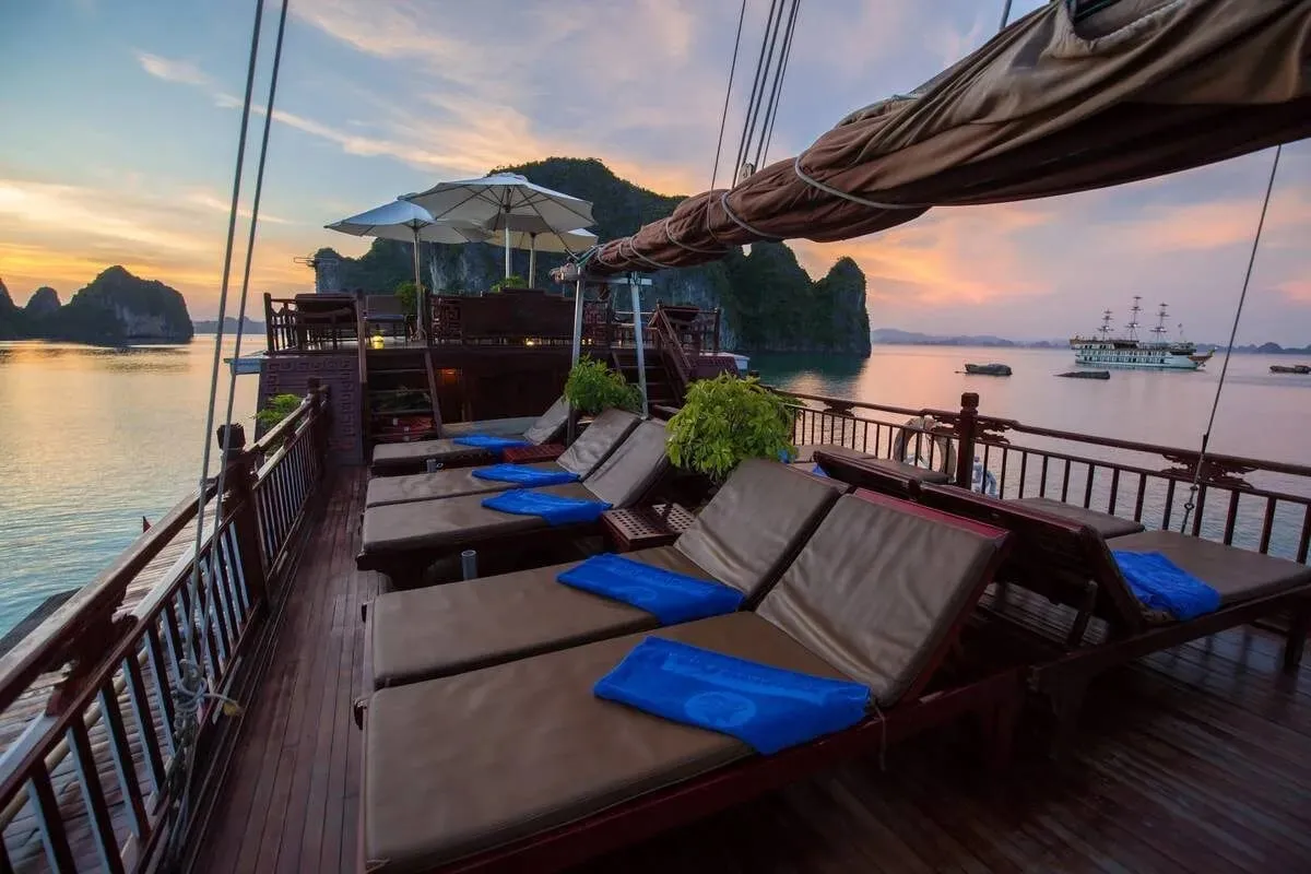 Brown sun loungers with blue cushions on the timber sundeck at sunset.