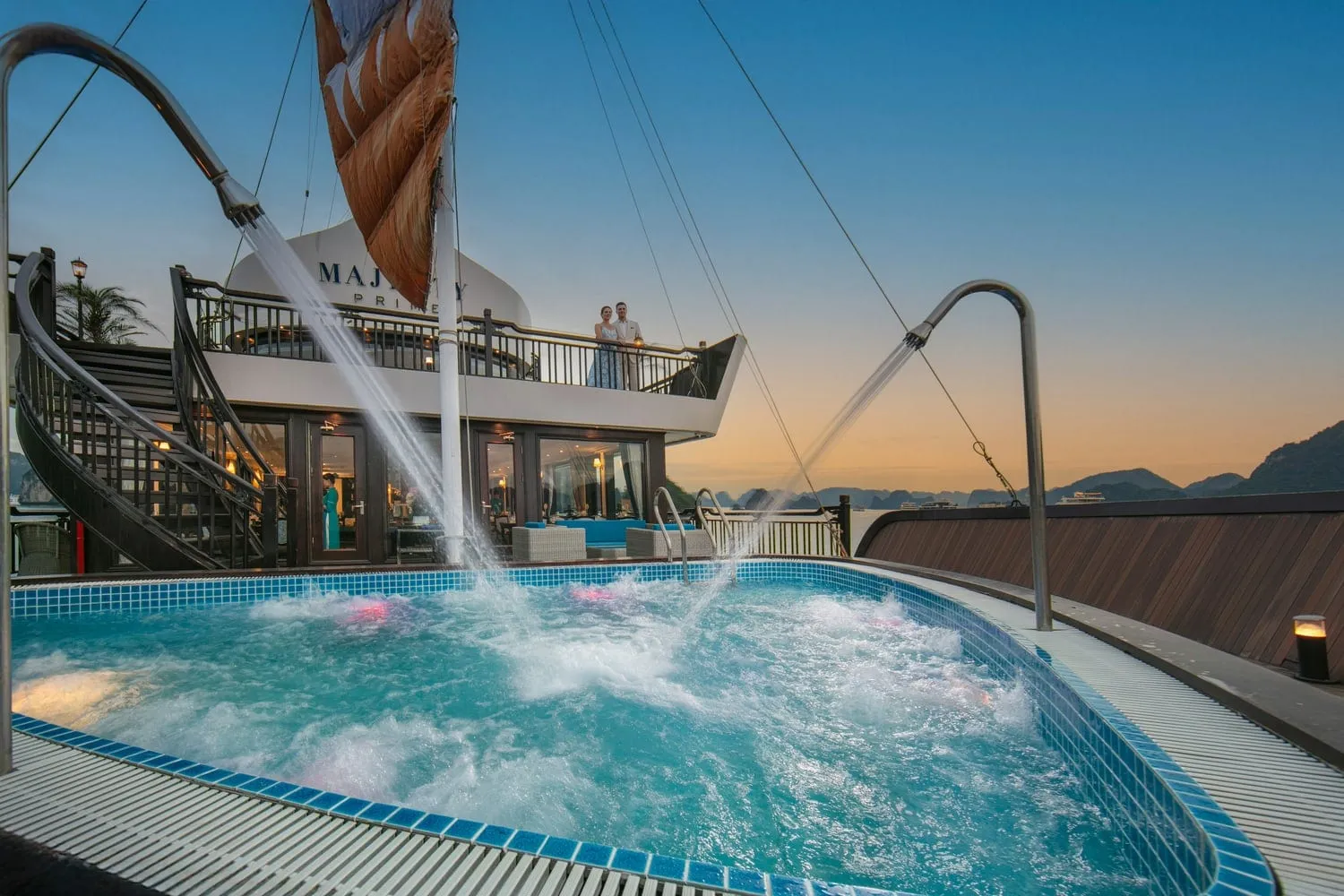 A deck pool with water jets on a cruise boat at sunset with limestone karsts visible in the background.