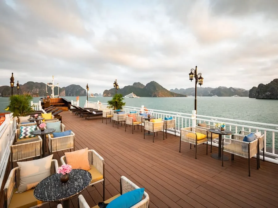 Wicker armchairs and a round table on the timber sundeck, with limestone islands in the background.