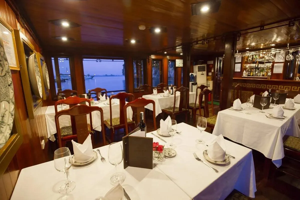 The indoor restaurant with white-clothed tables, dark timber panelling and a bar at the back.