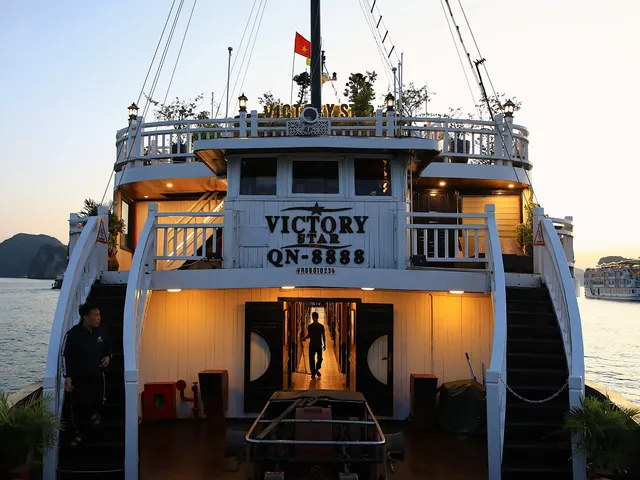 A white cruise boat named Victory Star QN-8888 docked at sunset with limestone karsts visible in the background and another boat in the distance.