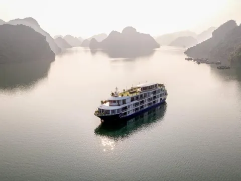 Mon Chéri alone on silver water in flat morning light, karst islands fading back into haze